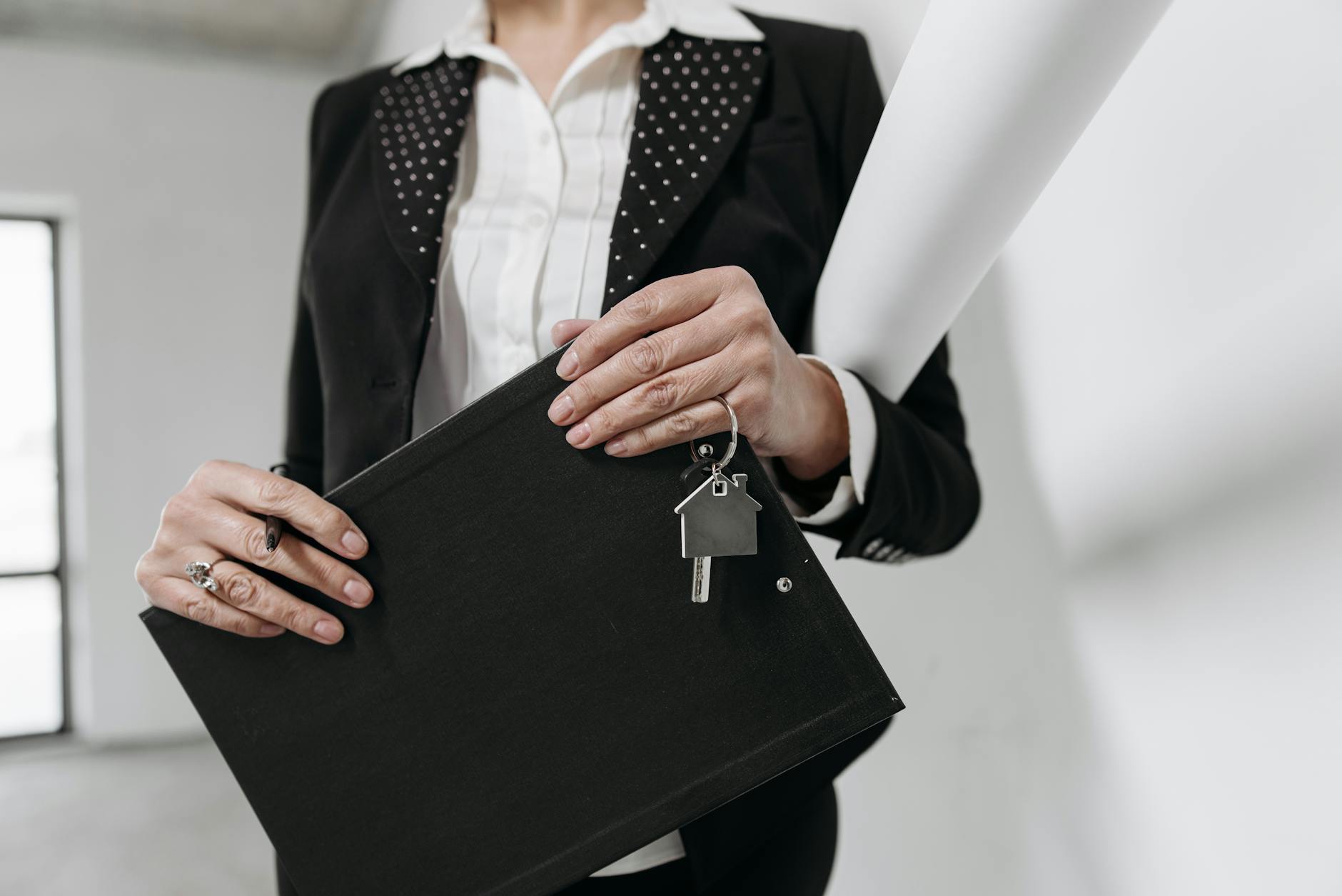 Partners Close-up of a realtor holding a keychain and clipboard with interior office background.